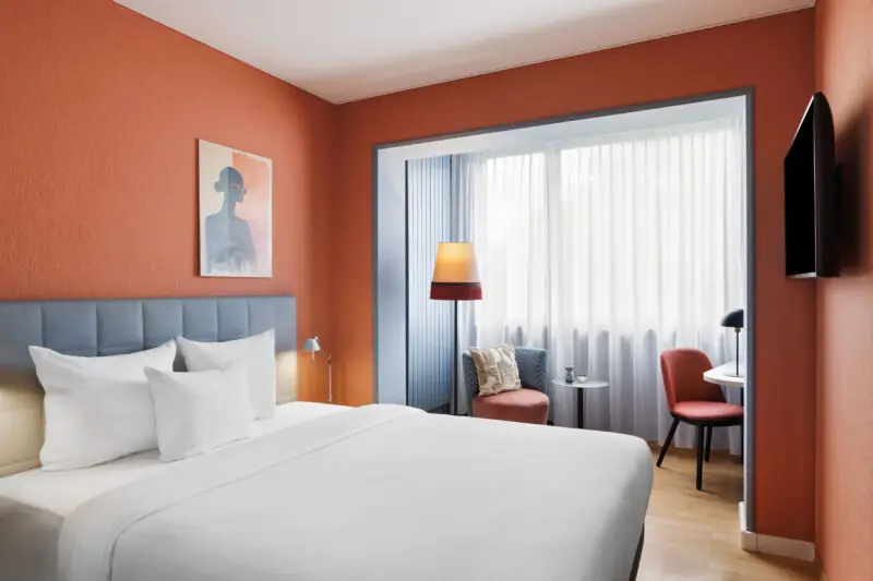 A business bedroom at Hotel La Pergola, showcasing orange walls and a well-arranged bed.