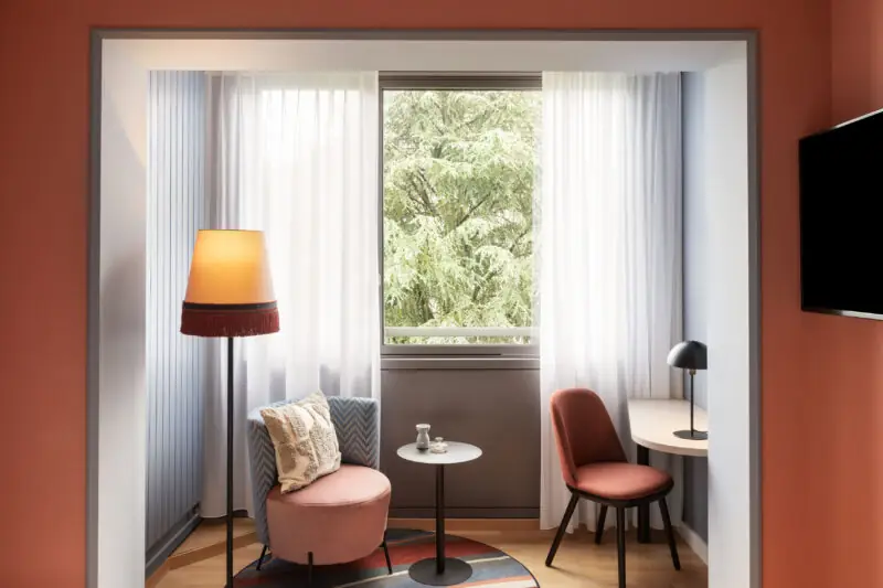 Cozy business bedroom at Hotel La Pergola with a chair, table, and lamp arranged for comfort.