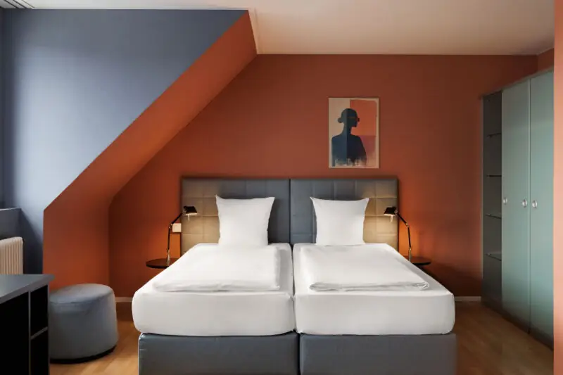 Hotel La Pergola's comfort room with two beds and a wall painting, creating a cozy atmosphere.  