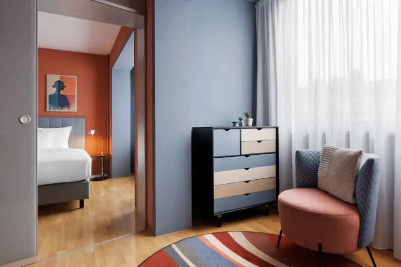 Hotel La Pergola family room showcasing a bed, a chair, and a mirror, designed for comfort and relaxation.  