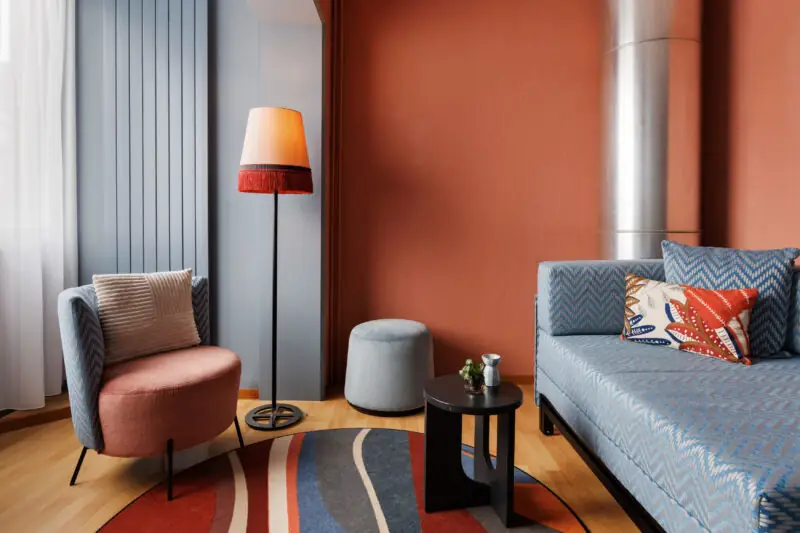 Family room at Hotel La Pergola featuring a couch, chair, and lamp in a cozy living space.  