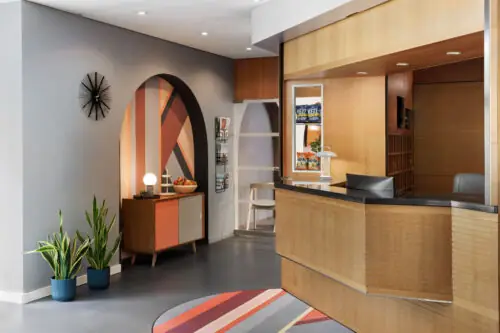 Stylish lobby of Hotel La Pergola with a contemporary reception desk and a lush green plant.