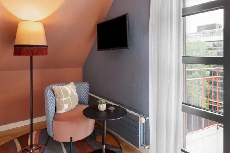 A small, inviting room at Hotel La Pergola with a chair, table, and TV for a comfortable stay.  