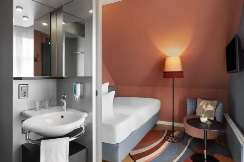 A single room at Hotel La Pergola with a sink, bed, and chair, offering a welcoming atmosphere for guests.  